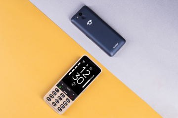 Two BlindShell Classic 3 phones in Ocean Blue and Golden Sand are displayed on a diagonally divided yellow and light gray background. One phone is shown from the front, highlighting its large high-contrast display and tactile physical keypad, while the second is shown from the back with the camera, SOS button, and BlindShell logo visible.