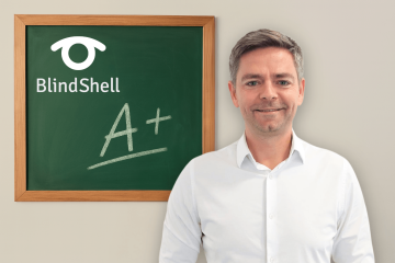 Jan Šimík, dyrektor BlindShell, stoi pewnie w białej koszuli obok tablicy z logo BlindShell i dużą oceną A+. Obraz emanuje pozytywną energią, będąc symbolem osiągnięć i przywództwa.