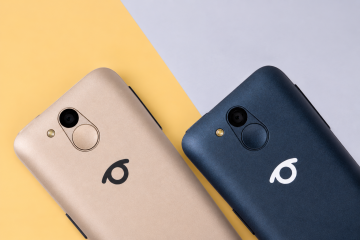 Close-up of two BlindShell Classic 3 phones in Golden Sand and Ocean Blue placed side by side on a soft yellow and light gray background. Both phones are shown from the back, highlighting the camera, flash, round SOS button, and BlindShell logo.