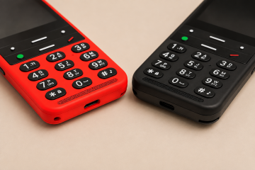 Close-up of two BlindShell Classic 2 phones in red and black placed side by side on a warm beige background. The image focuses on their large tactile keypads, clearly distinguishable buttons, speaker grilles, and charging ports.