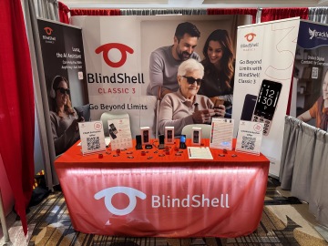 El stand del BlindShell Classic 3, con su distintivo color rojo, pancartas con información sobre productos y un espacio de presentación atractivo con teléfonos móviles accesibles. Esta disposición refleja nuestras innovaciones, independencia y enfoque en tecnologías asistivas.