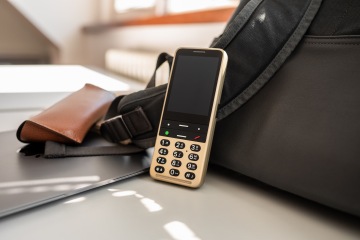 BlindShell classic 3 è su un tavolo accanto a una borsa nera, l'intera immagine ha un'impostazione professionale.