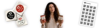 Una donna non vedente confusa tiene in mano due contenitori di spezie cercando di distinguerli. Uno è etichettato Chilli e l’altro Cinnamon. Sul lato sinistro dell’immagine si vedono tag NFC BlindShell neri, bianchi e arancioni. Sul lato destro si trova un foglio di codici QR BlindShell. I tag NFC e i codici QR possono aiutare a distinguere oggetti che altrimenti sarebbero difficili da identificare.