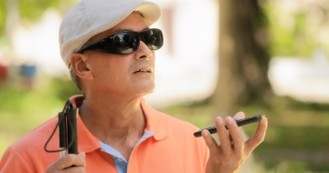 An older man with mobile phone. He is using voice control